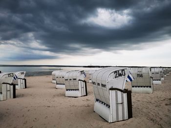 Hooded chairs on beach against sky