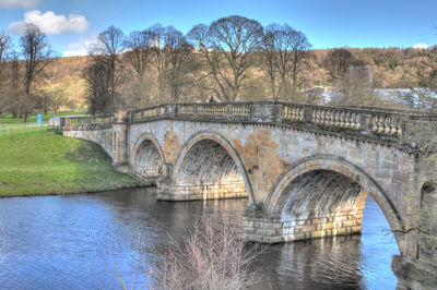 Bridge over river in city against sky