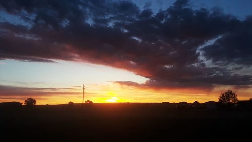 Scenic view of silhouette landscape against dramatic sky during sunset