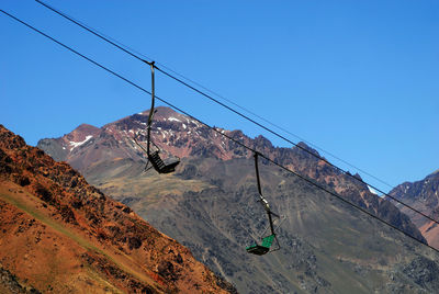 Overhead cable car over mountains against clear blue sky