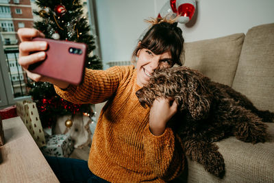 Young woman using mobile phone on sofa at home