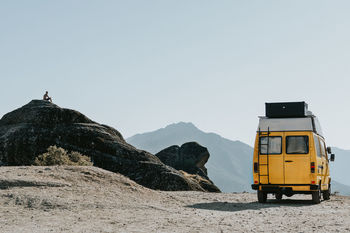 Vehicle parked on mountain against clear sky