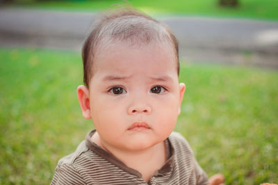 Close-up portrait of cute baby boy sitting at park