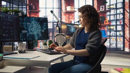 Side view of young woman using laptop while sitting at airport