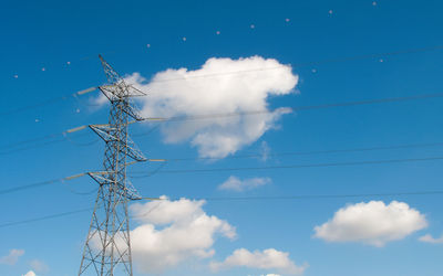 Low angle view of electricity pylon against blue sky