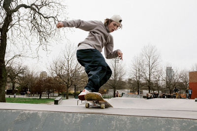 Man skateboarding on sports ramp against clear sky at park