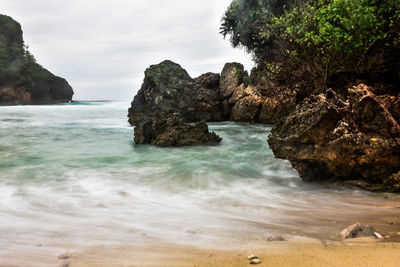 Rock formation on beach against sky