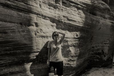 Portrait of woman wearing sunglasses standing against rock formation