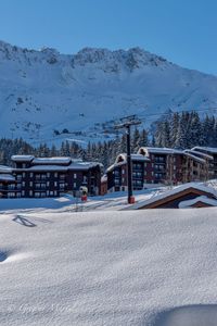 Houses by snow covered mountains against clear sky