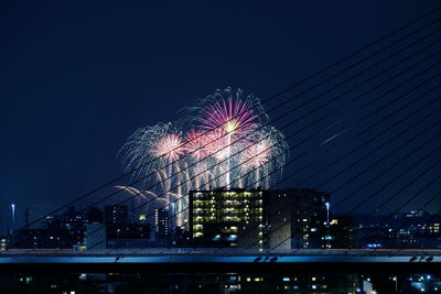 Low angle view of illuminated ferris wheel against buildings at night