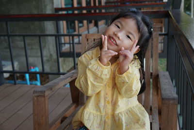 Portrait of cute smiling girl gesturing while sitting on chair