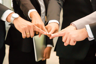 Midsection of business people touching fingers at office
