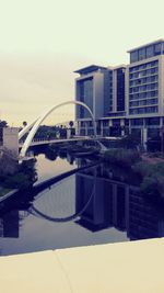 Reflection of bridge in city against sky