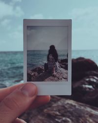 Midsection of person photographing sea against sky