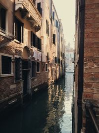 Canal amidst buildings in city against sky