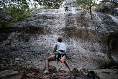 Rear view of men climbing rock