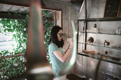 Side view of young woman looking through window