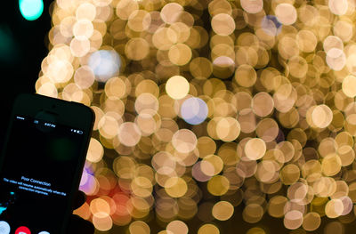 Close-up of mobile phone against illuminated lights