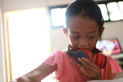 Close-up of girl wearing headphones while sitting at home