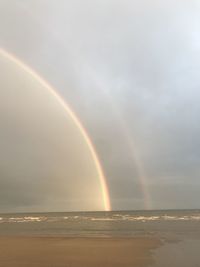 Scenic view of rainbow over sea against sky