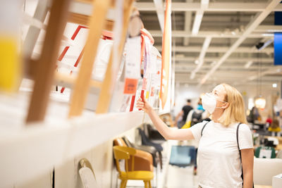 Side view of woman wearing mask standing at store