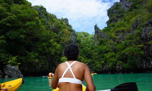 Rear view of woman on river against trees