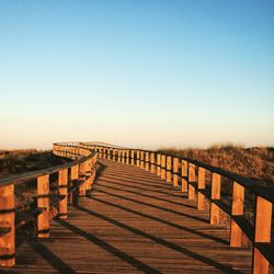 Footbridge over field against clear sky