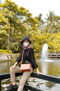 Portrait of woman wearing mask by railing against fountain