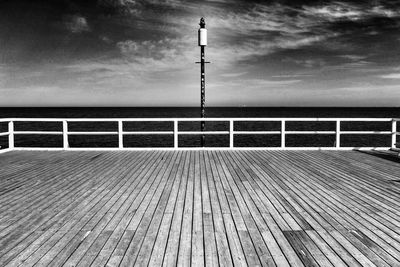 Pier on sea against cloudy sky