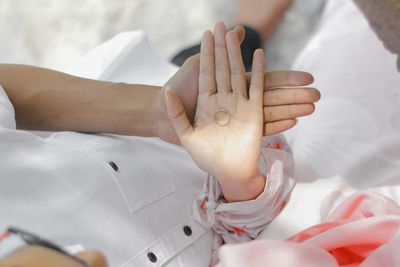 Close-up of hands lying on bed
