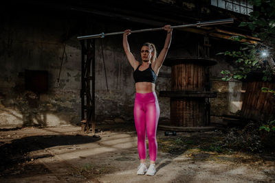 Full length of woman standing by pink umbrella