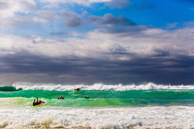 People surfing in sea against sky