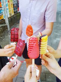 Midsection of friends holding colorful ice cream