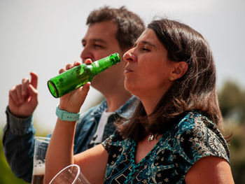 Man and woman drinking beer against sky