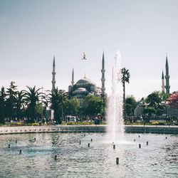 Fountain in front of temple against clear sky