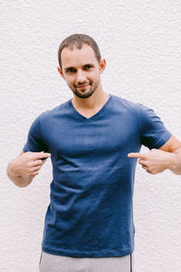 Portrait of man gesturing while standing against white wall