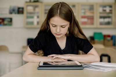 Female student looking at digital tablet while sitting in classroom