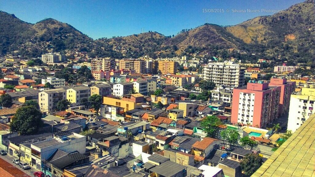 building exterior, architecture, built structure, mountain, residential district, high angle view, crowded, cityscape, residential structure, city, residential building, mountain range, town, house, clear sky, townscape, sky, outdoors, blue, roof