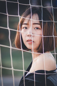 Portrait of beautiful young woman standing at goalpost