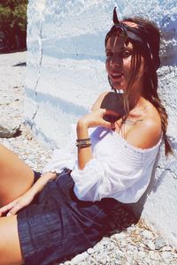 Portrait of young woman sitting by white wall