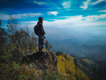 Man standing on rock against sky