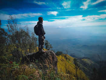 Full length of man standing on rock against sky