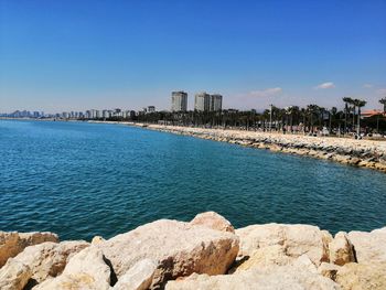 Scenic view of sea by buildings against clear blue sky