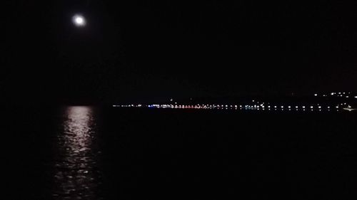 Illuminated lights in river against sky at night