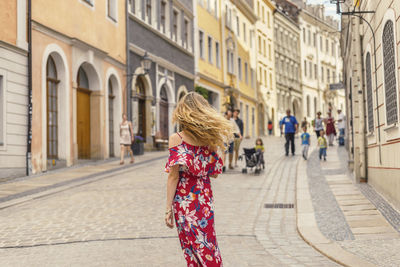 Rear view of woman standing on street in city