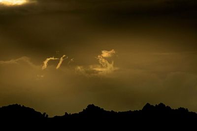 Silhouette of mountain against cloudy sky at sunset