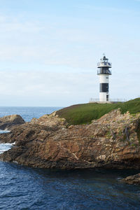 Lighthouse by sea against sky