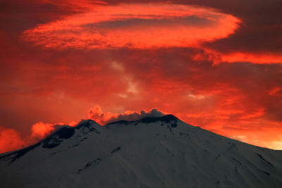 Scenic view of snowcapped mountains against orange sky