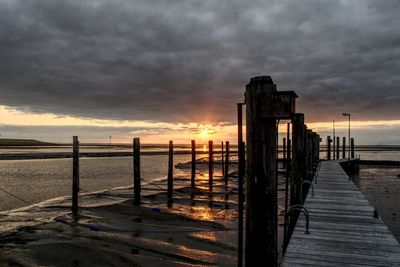 Pier over sea against sky during sunset