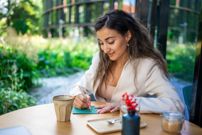 Young woman using mobile phone while sitting on table